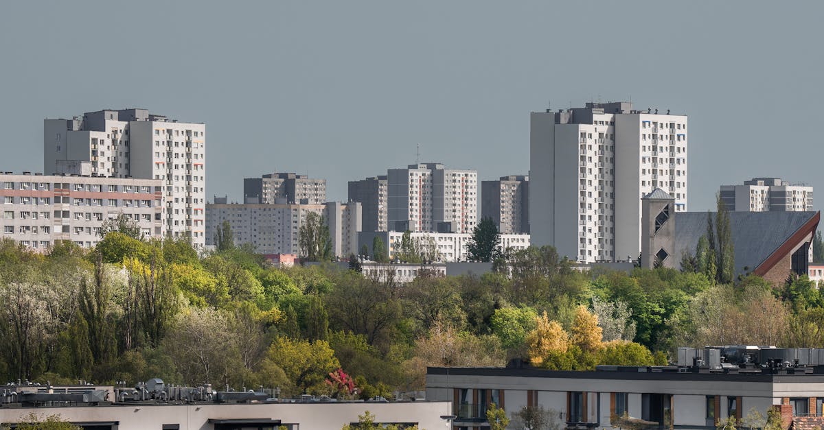 Urban skyline view of residential buildings in Poznań, surrounded by lush greenery.
